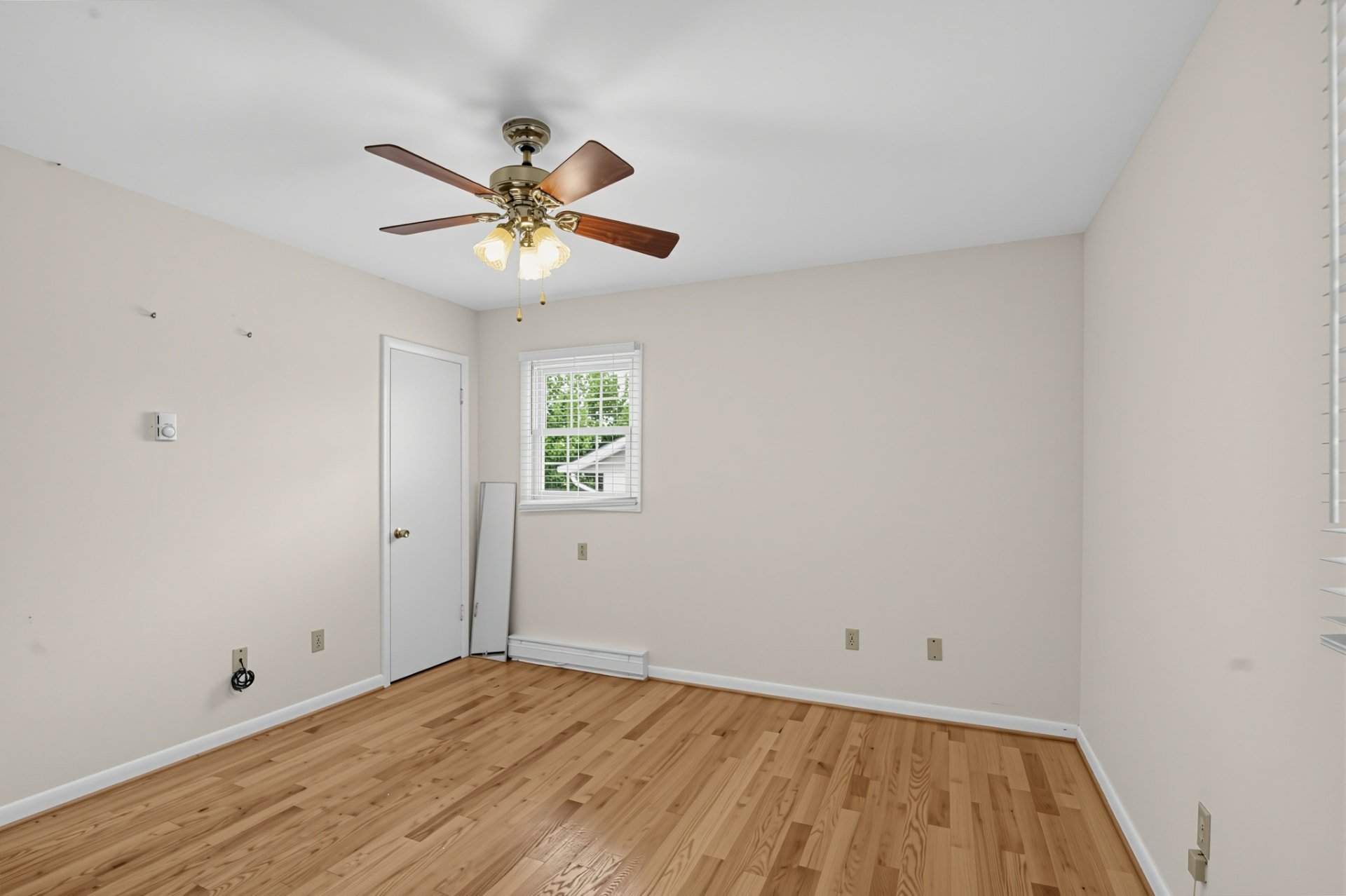 Second bedroom with hardwood floors, ceiling fan and a window to the yard
