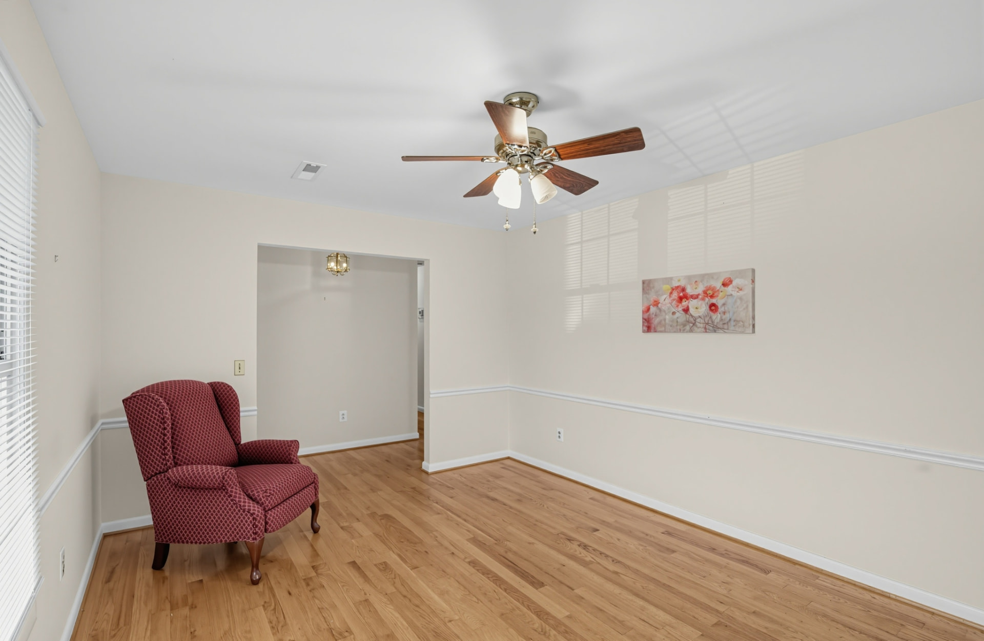 Living room with oak hardwood floors, chair rail trim and a ceiling fan