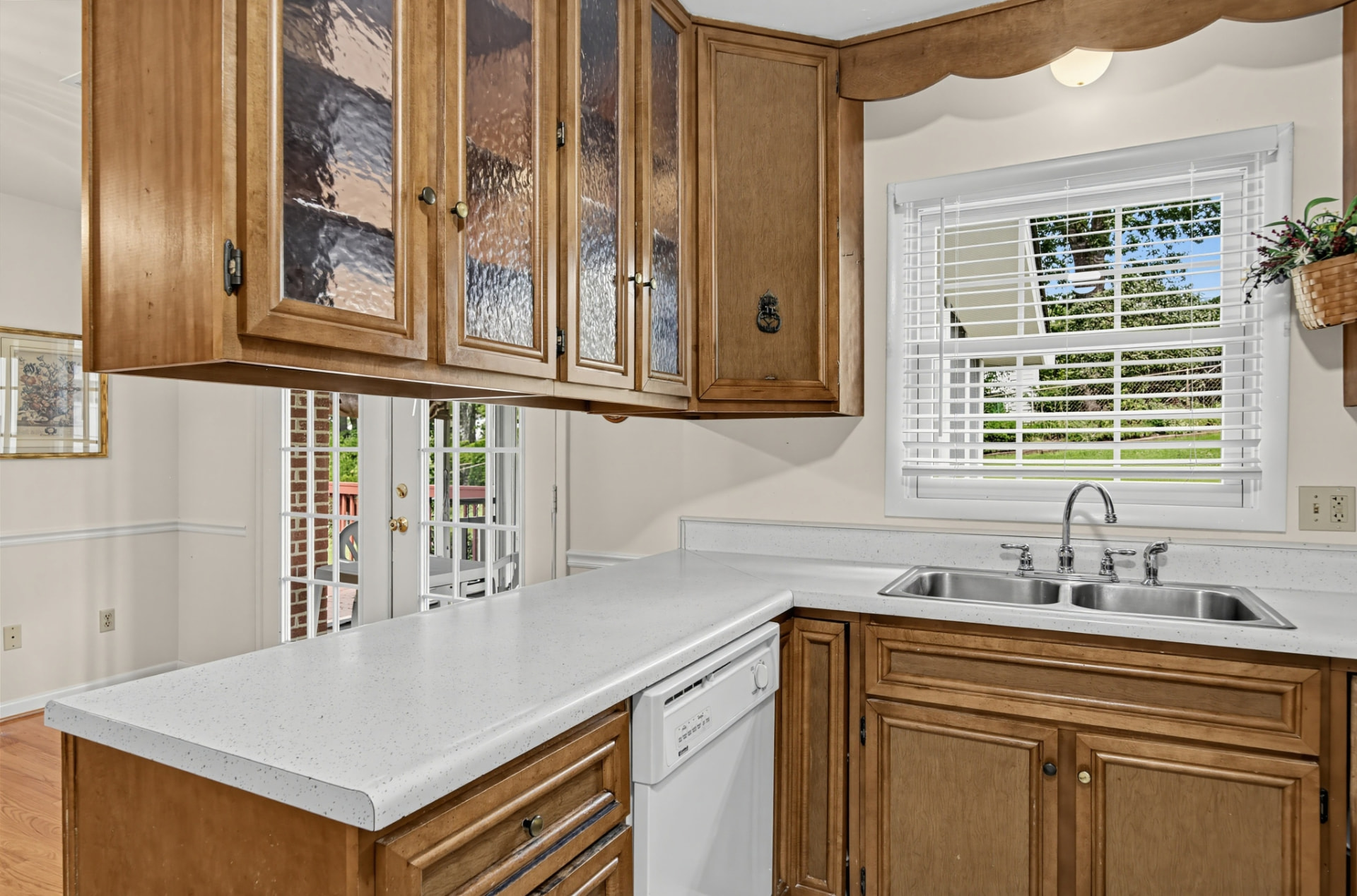 Kitchen counter and sink beneath a window, with French doors to the deck